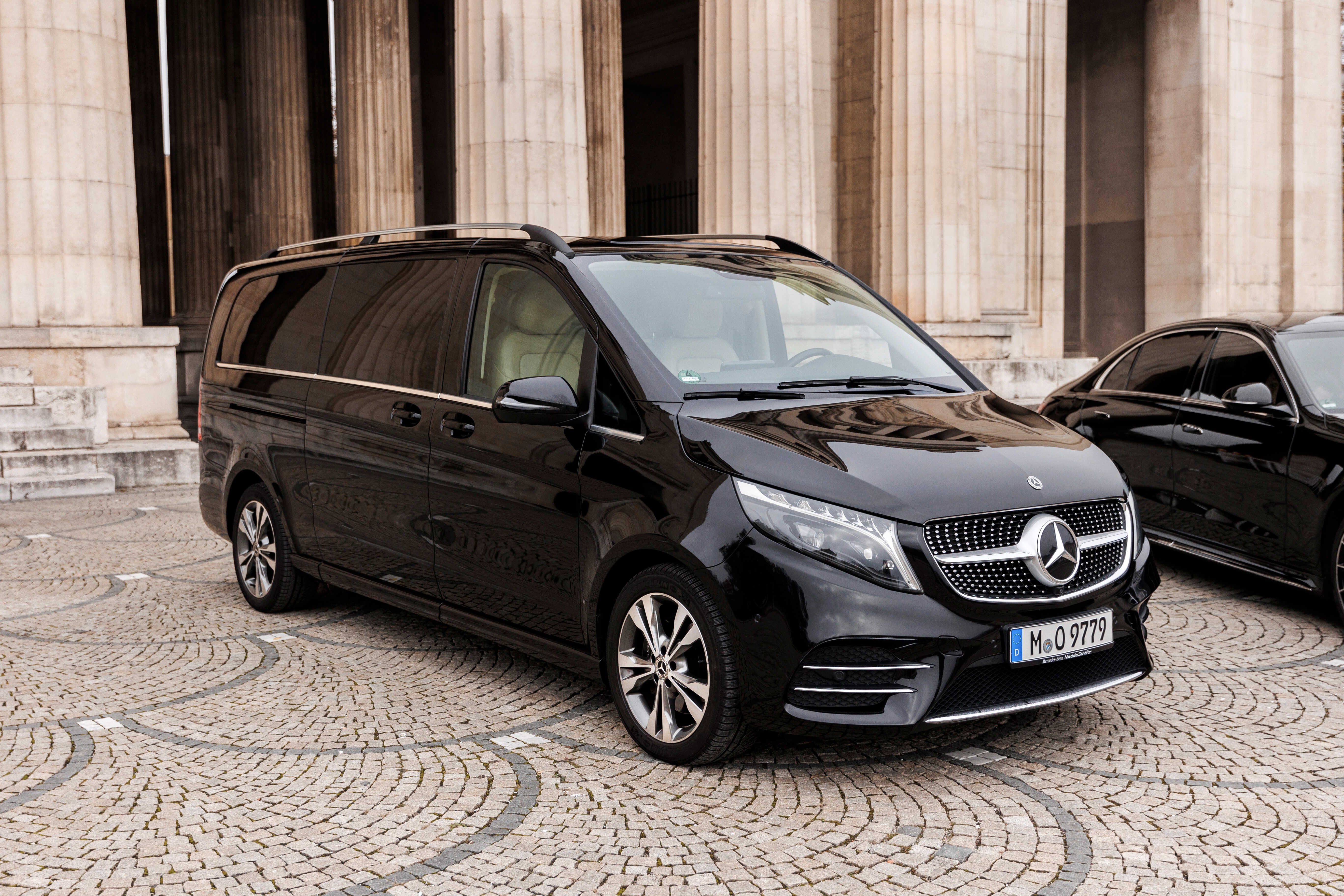 Schwarze Mercedes V-Klasse vor klassischem Gebäude in München - Airport Transfer Service